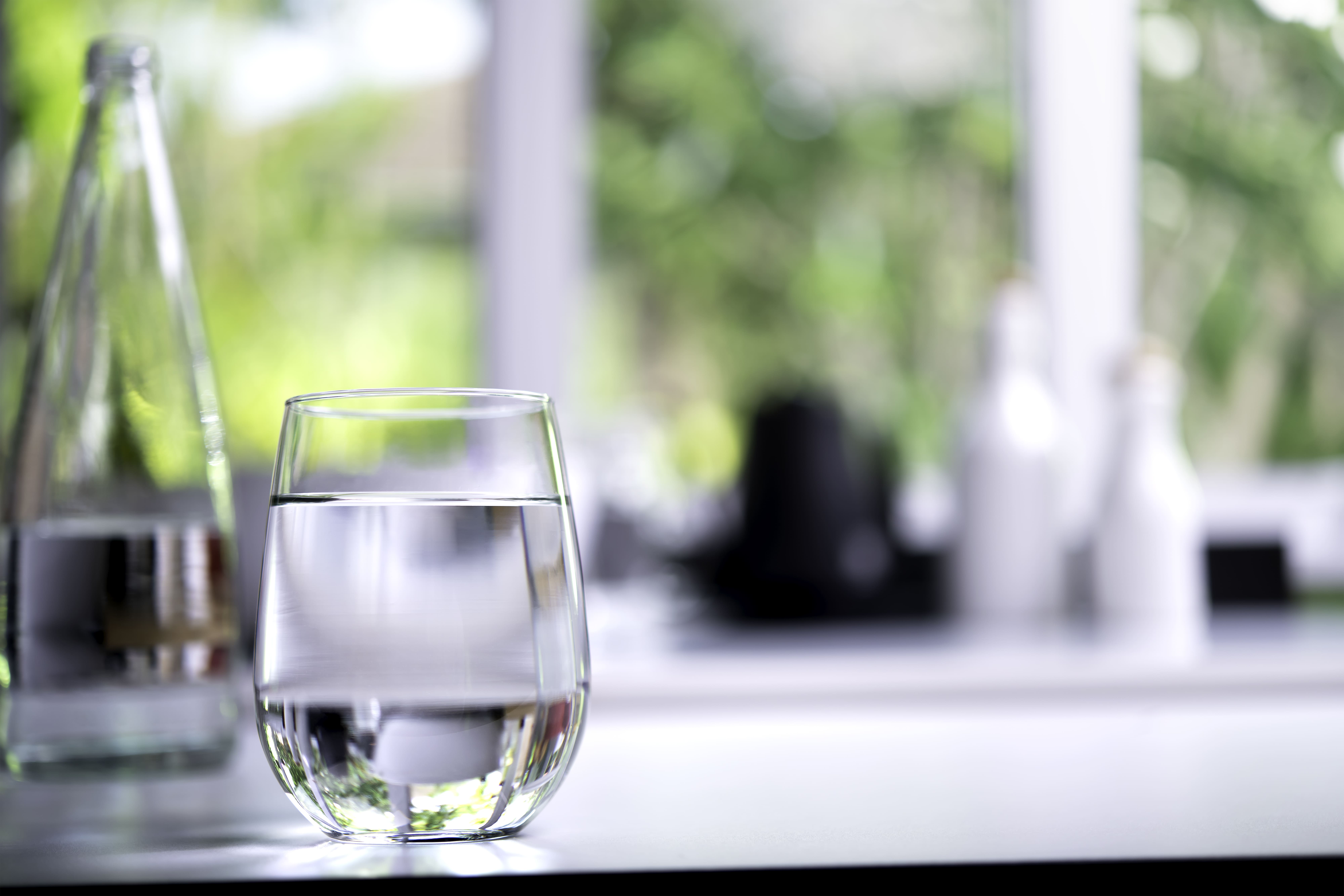 Vaso de agua filtrada del grifo en cocina moderna con luz natural, alternativa sostenible al agua embotellada