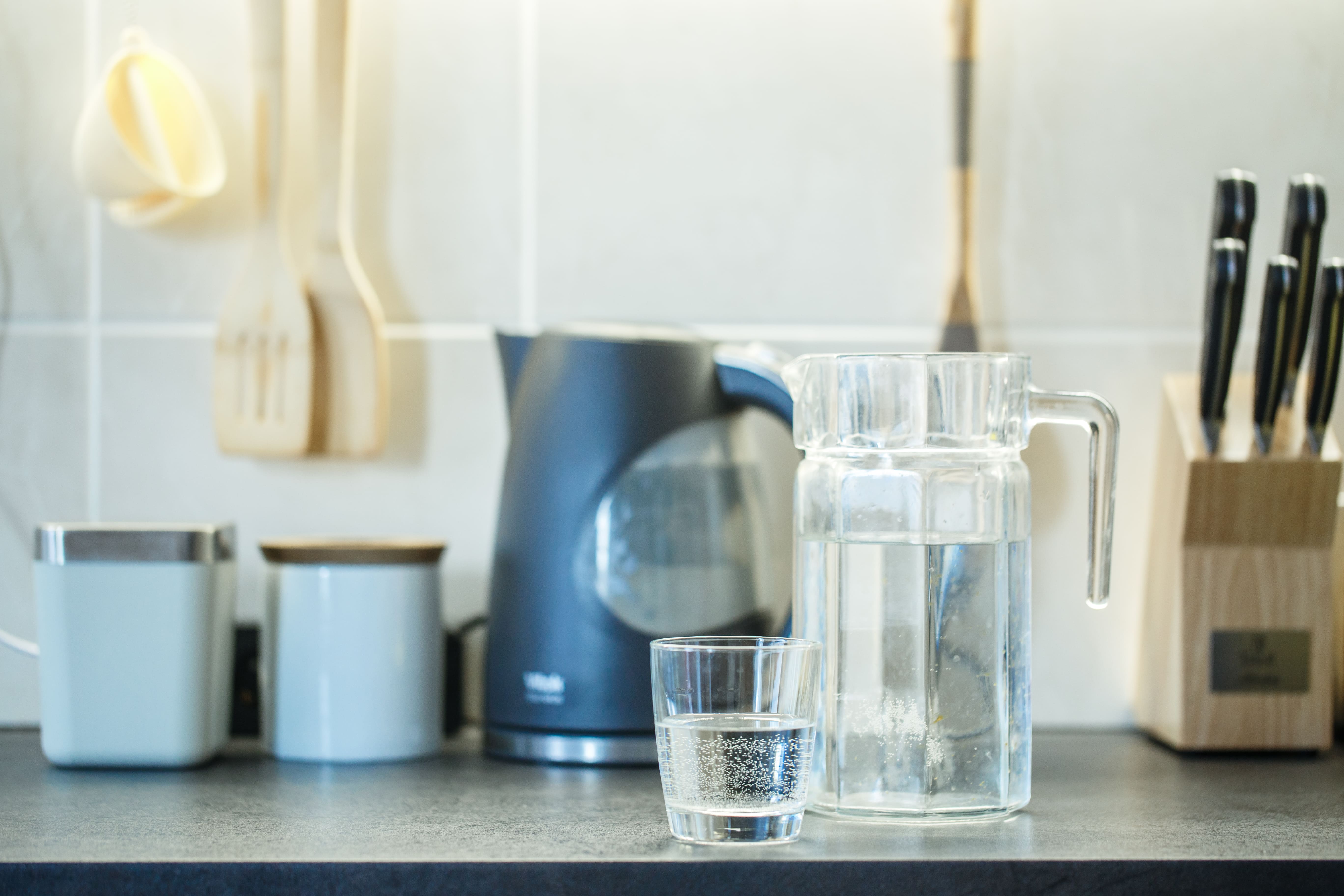 Jarra y vaso con agua filtrada fresca en cocina doméstica como alternativa al agua embotellada