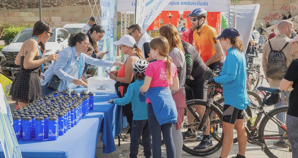 Stand Tuawa con botellas reutilizables en evento ciclista promoviendo agua sostenible